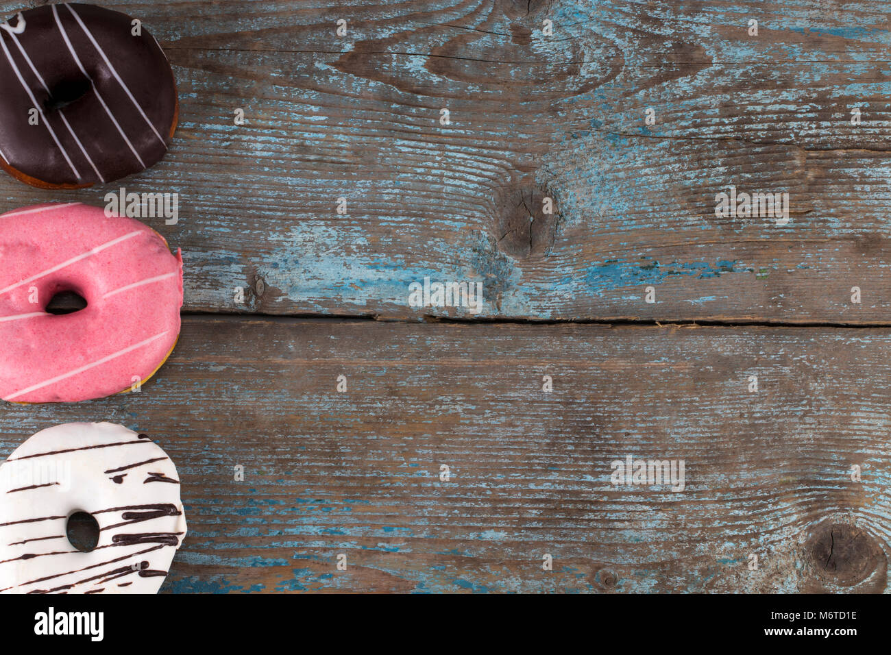 Donuts in a glaze assorted on a wooden table. With copy space. Top view ...