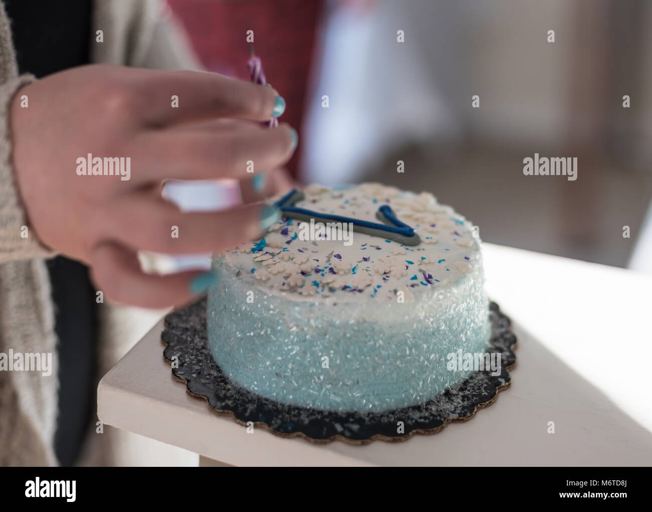 macro closeup of hand putting candle on cake for first birthday