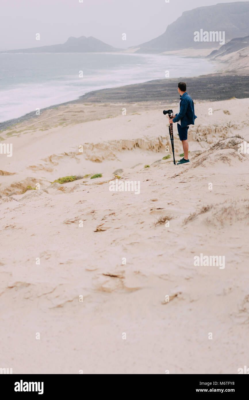 Photographer with camera in desert admitting unique landscape of sand ...