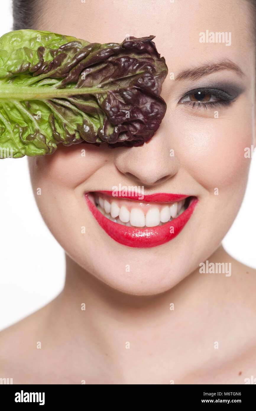 Smiling woman with lettuce leaf over her eye Stock Photo