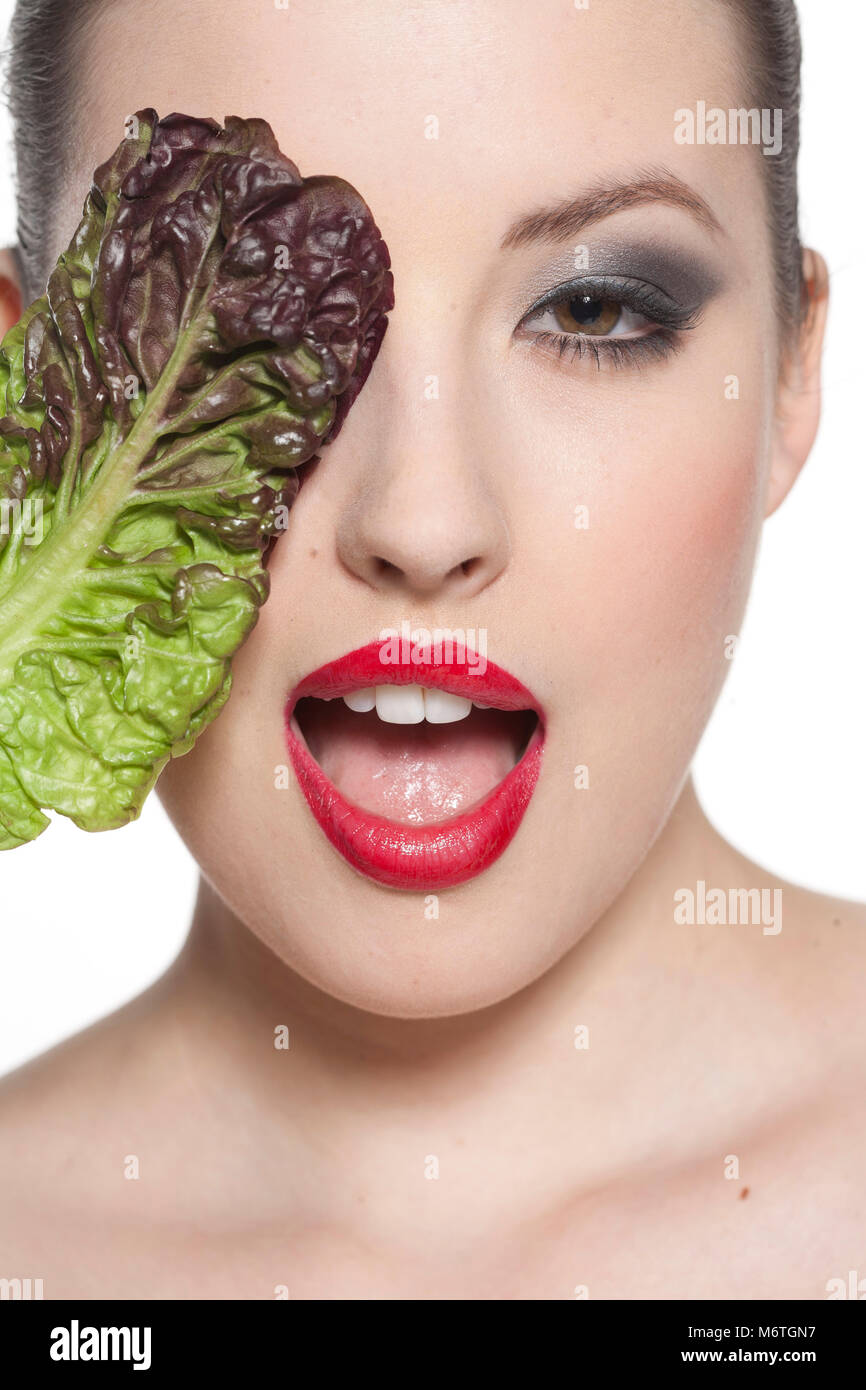 Woman with lettuce leaf over her eye Stock Photo