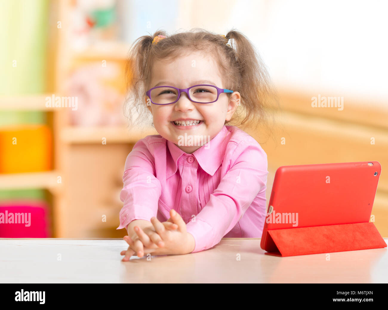 Smart kid in glasses reading books sitting at table at her room Stock Photo