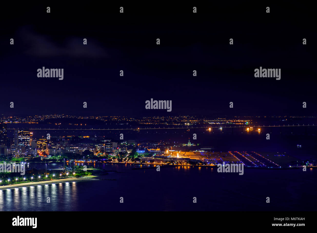 Night view of the top of the Santos Dumont airport at downtown of Rio de Janeiro with lights, buildings and Rio Niteroi bridge at background Stock Photo