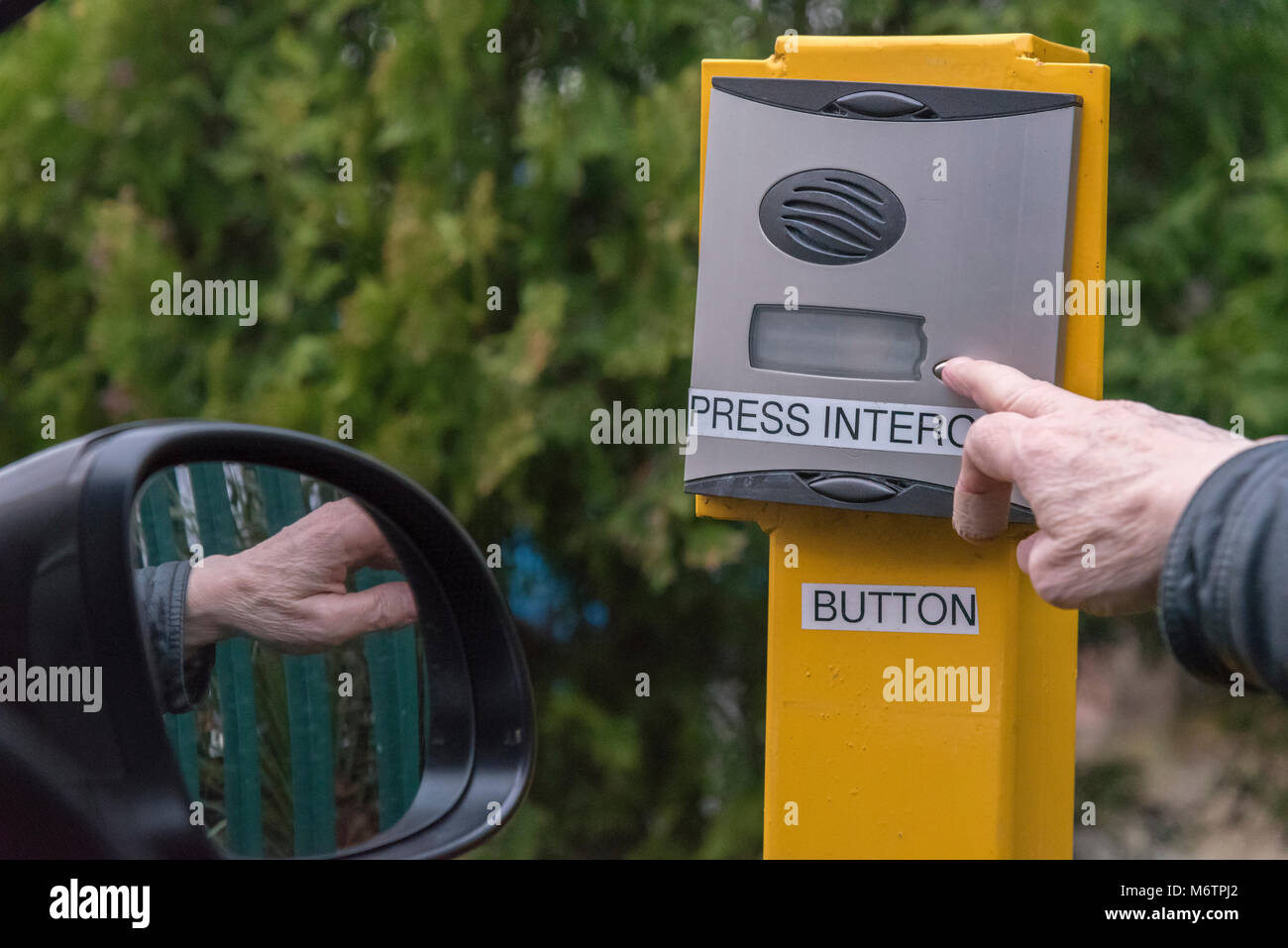 Hand pushing car park security intercom button Stock Photo