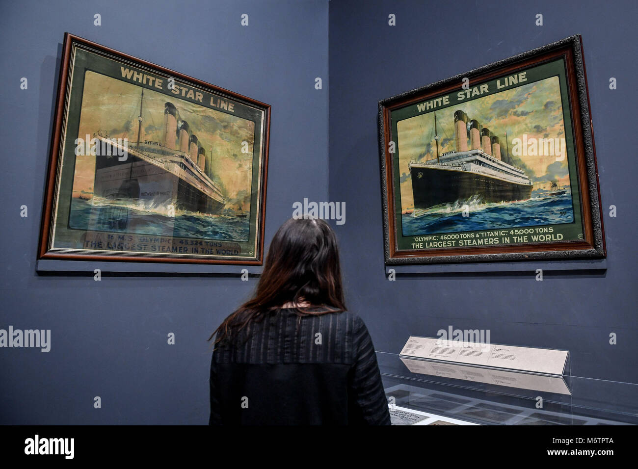 A woman looks at two publicity posters from the White Star Line company, during a preview of the Titanic Stories exhibition at the National Maritime Museum Cornwall, Falmouth, which opens on March 8. Stock Photo