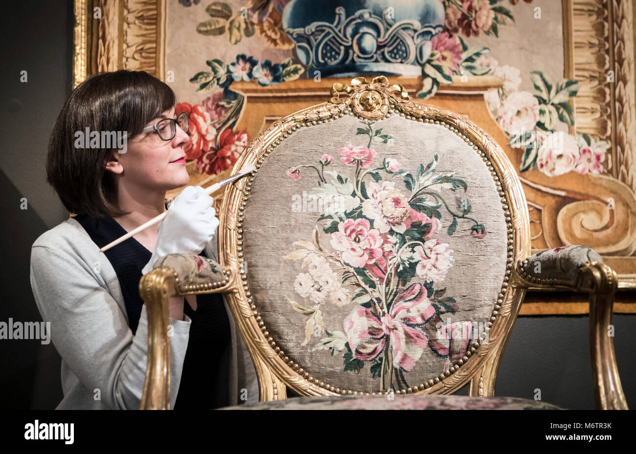Exhibition curator Ruth Martin uses a paint brush to dust a 1774 carved and gilded limewood chair, designed by Thomas Chippendale at Leeds City Museum, which is features in the Chippendale 300 exhibition. Stock Photo