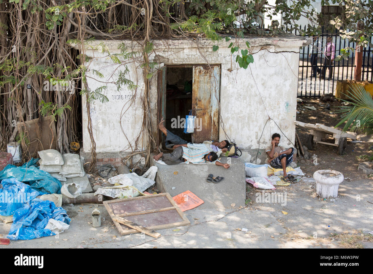 Indian men sleeping outside small building at Mumbai Port, India Stock Photo