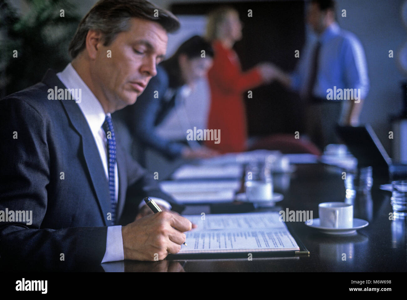 1997 HISTORICAL CAUCASIAN BUSINESS MAN SIGNING PAPERS AT CONFERENCE ...