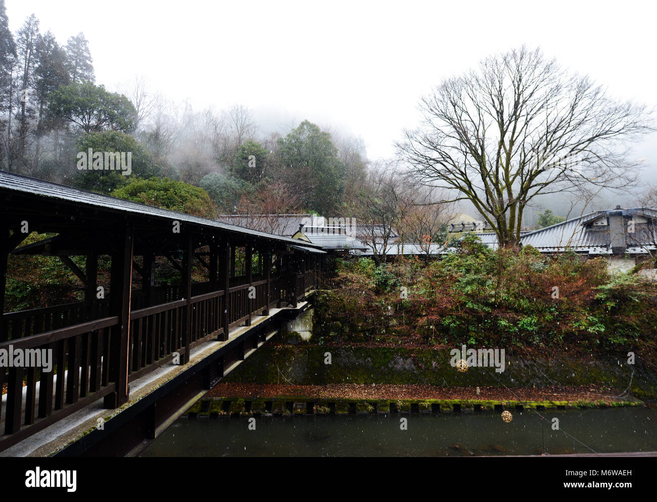 A wooden bridge connecting a riverside ryokan and the center of Kurokawa onsen town. Stock Photo