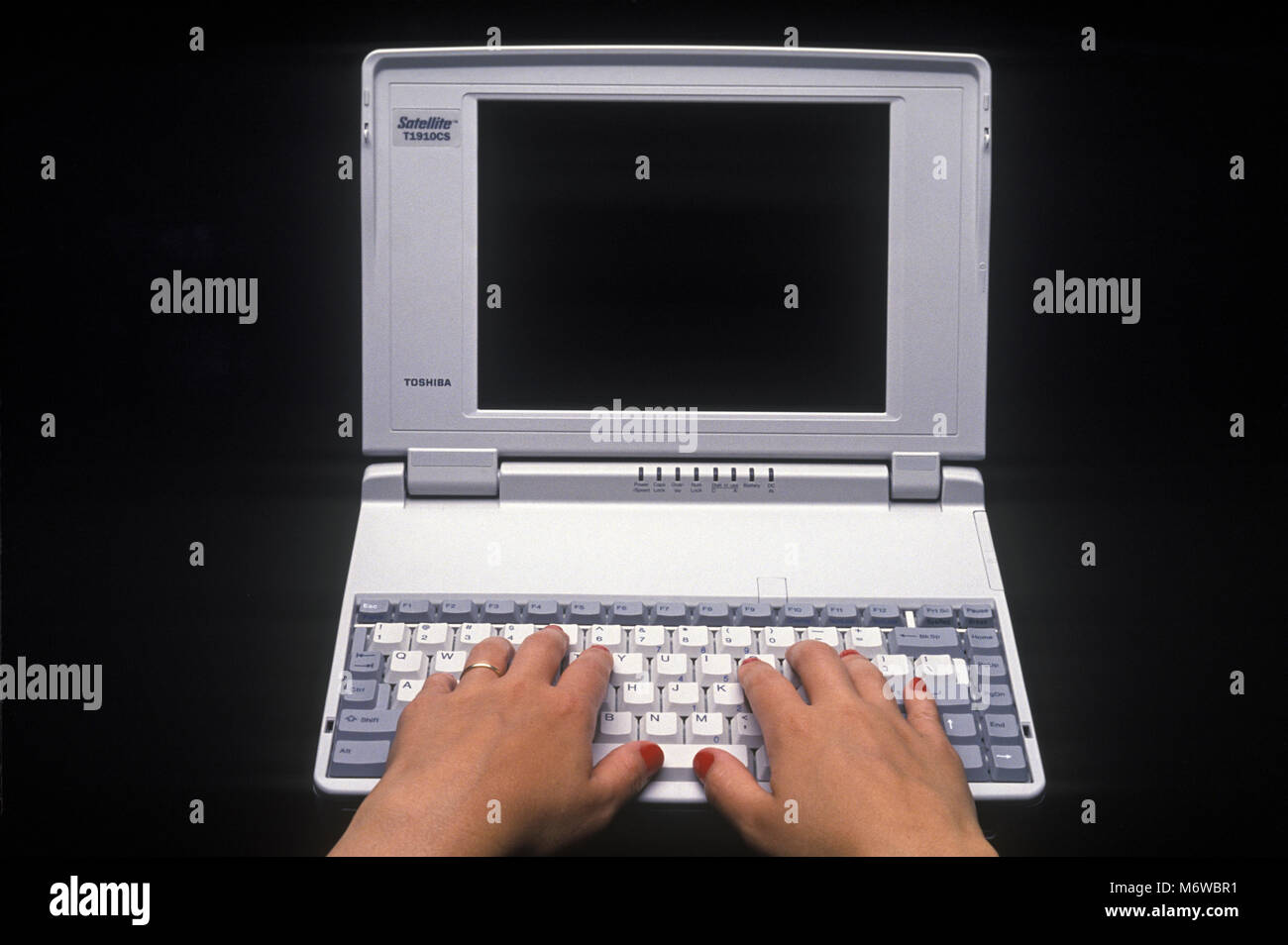 1994 HISTORICAL WOMANS HANDS TYPING OVER MECHANICAL KEYBOARD OF TOSHIBA T1910CS SATELLITE LAPTOP NOTEBOOK COMPUTER (©TOSHIBA CORP 1994) Stock Photo
