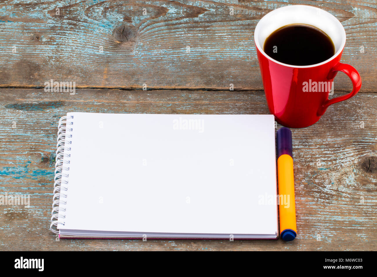 top view image of open notebook with blank pages next to cup of coffee on wooden table. ready for adding text or mockup. Stock Photo