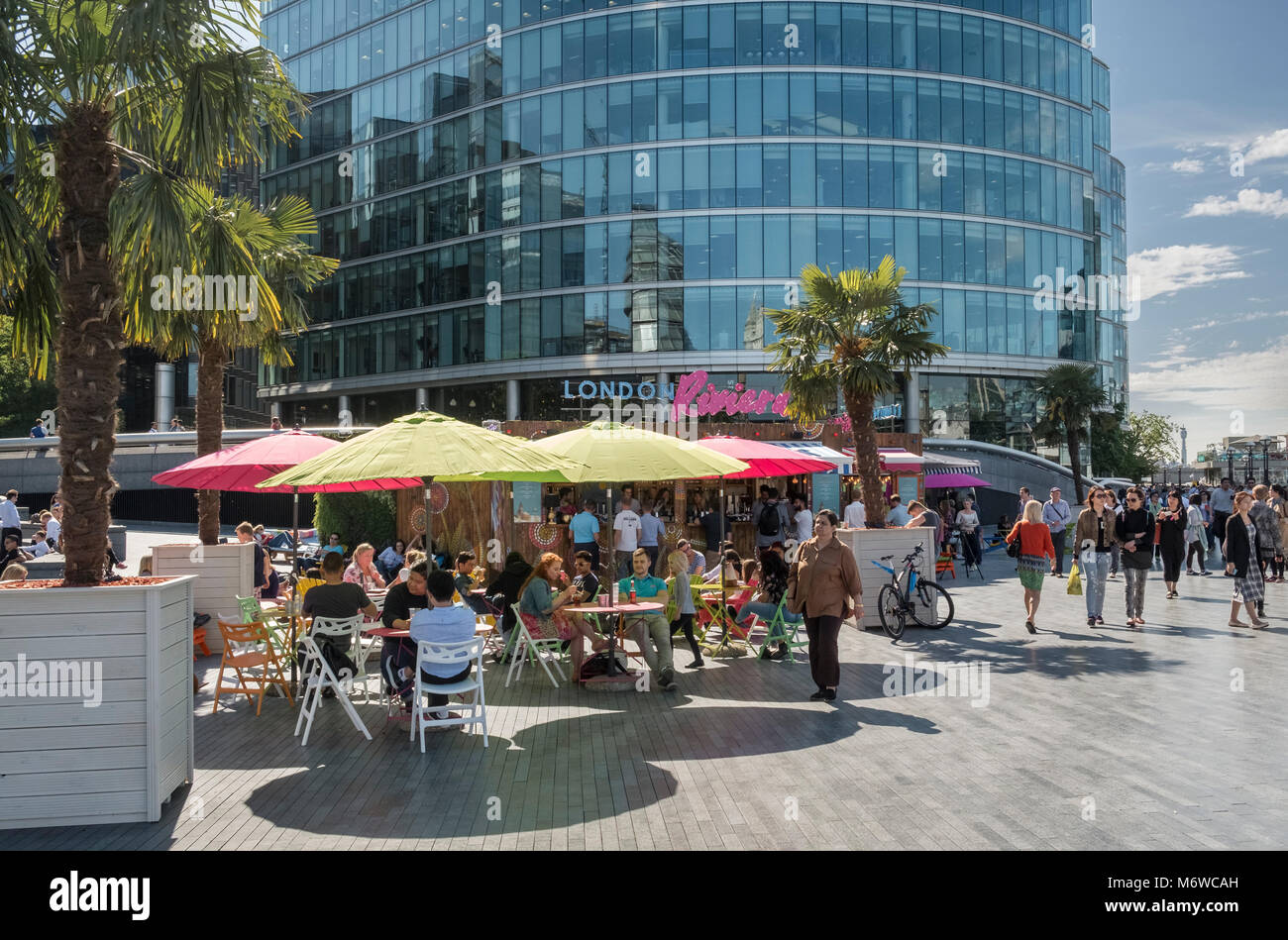 People sitting in summer sunshine at the London Riviera pop up restaurant on the Southbank, London, UK Stock Photo