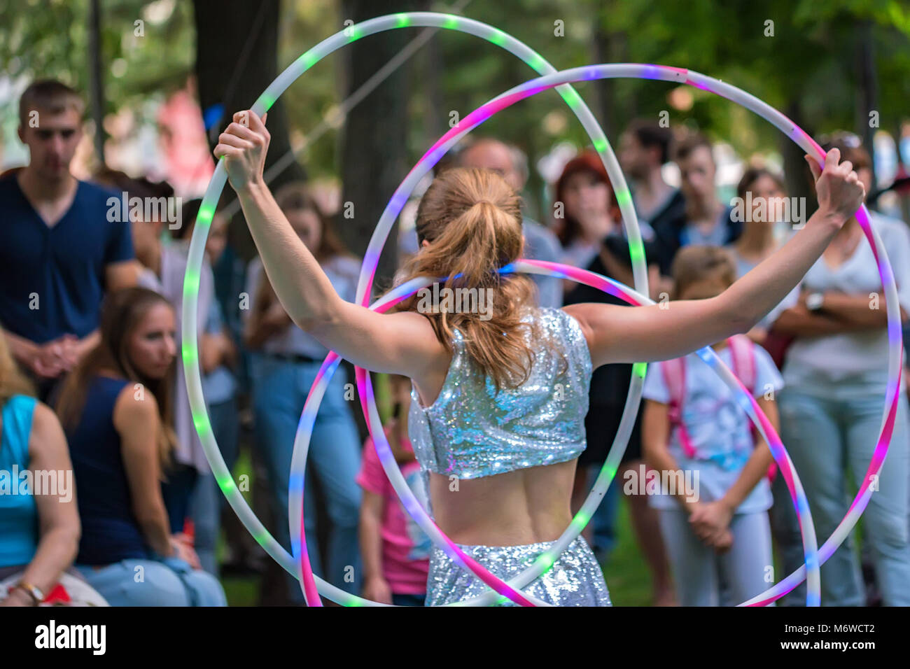 Girl in beautiful dress performs with hula hoops Stock Photo