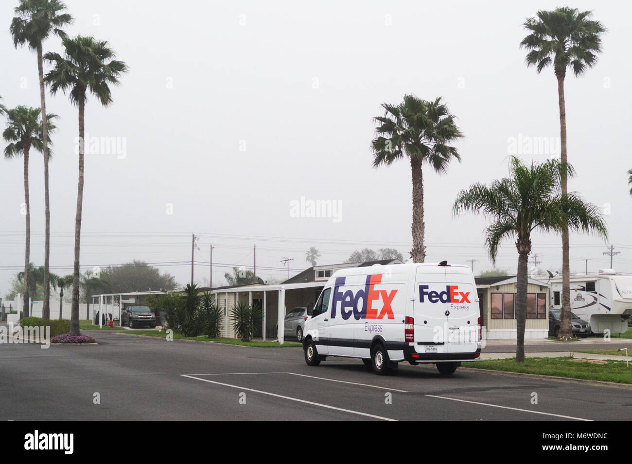 FedEx truck makes deliveries in an RV mobile home park in south Texas on a dreary, overcast day. Stock Photo