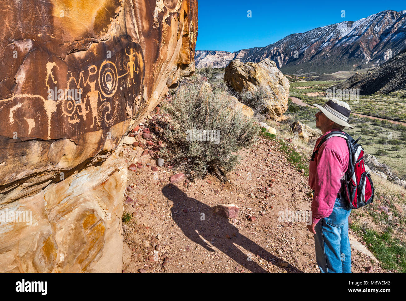 Hiker at McKee Springs Petroglyphs, Fremont culture,  Split Mountain in background, Island Park Road,  Dinosaur National Monument, Utah, USA Stock Photo