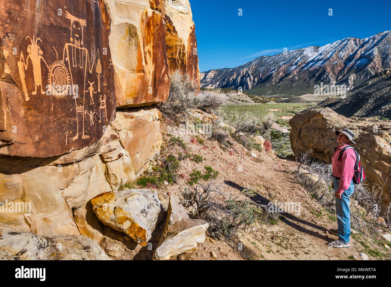 Hiker at McKee Springs Petroglyphs, Fremont culture,  Split Mountain in background, Island Park Road,  Dinosaur National Monument, Utah, USA Stock Photo