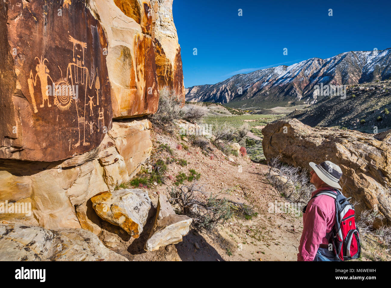 Hiker at McKee Springs Petroglyphs, Fremont culture,  Split Mountain in background, Island Park Road,  Dinosaur National Monument, Utah, USA Stock Photo