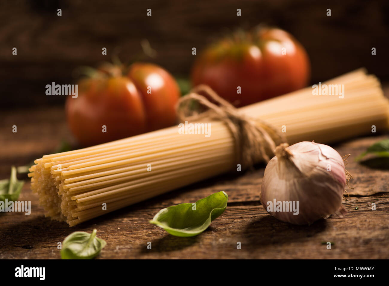 Spaghetti and tomatoes with herbs on an old and vintage wooden table ...