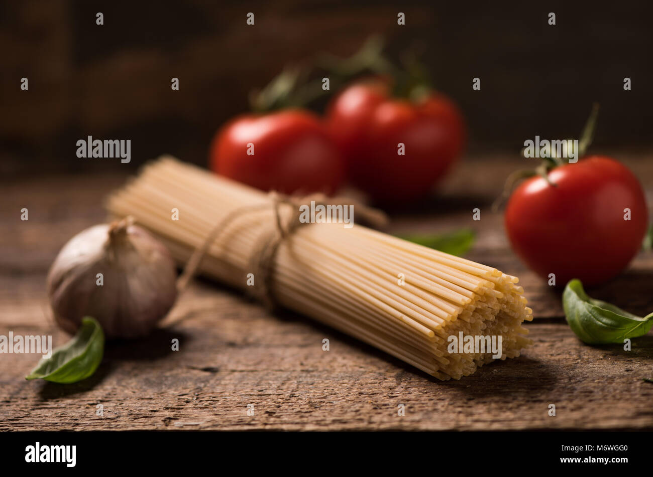 Spaghetti and tomatoes with herbs on an old and vintage wooden table ...