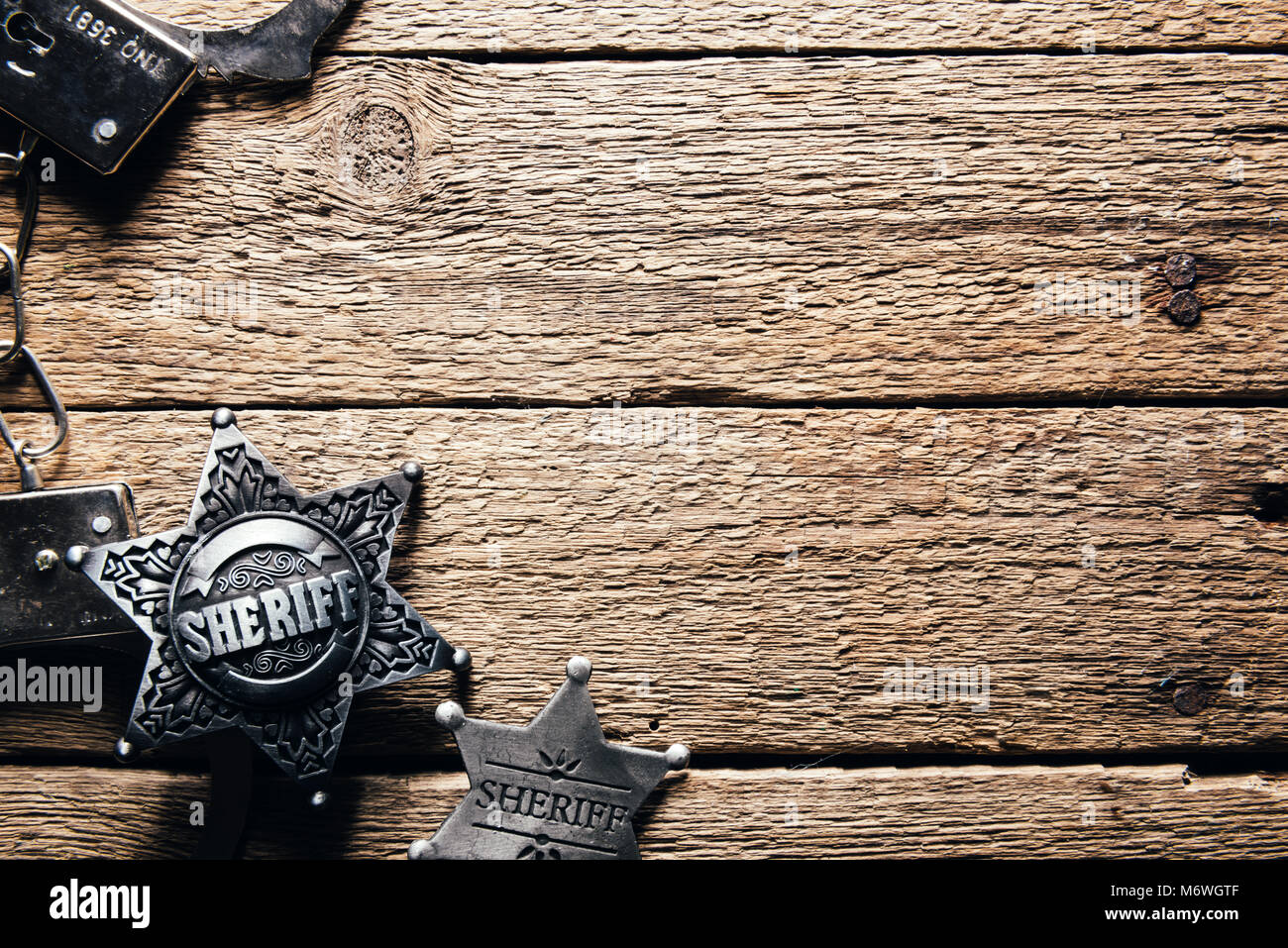 Sheriff star and handcuffs on wooden table Stock Photo