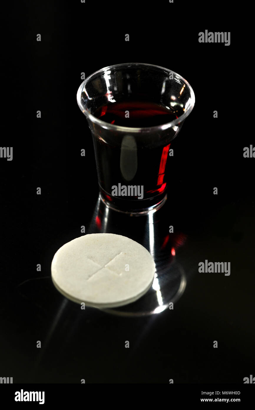 Communion wafer and cup with wine over dark background Stock Photo