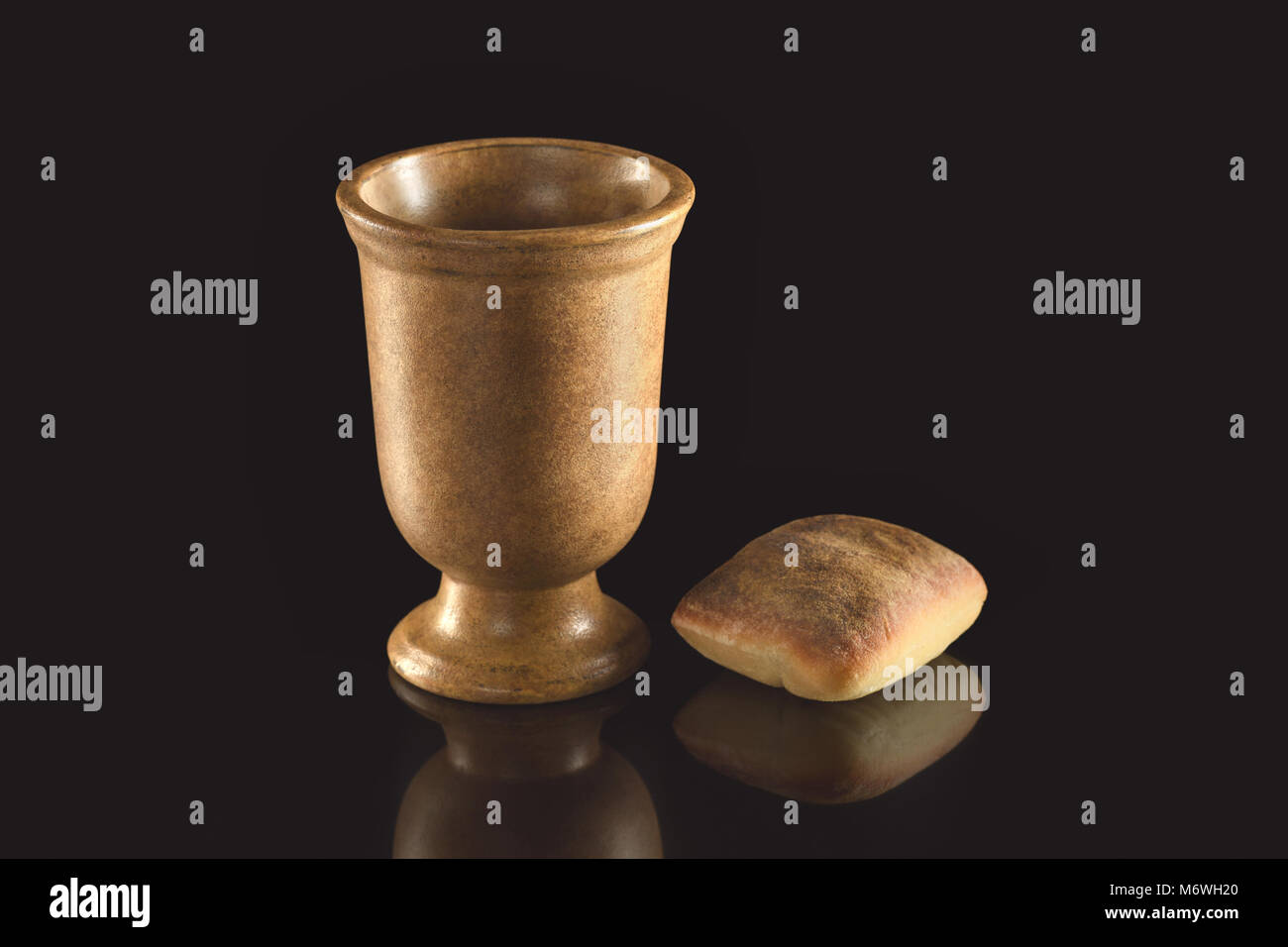 Cup of wine and bread on reflective table over dark background Stock Photo