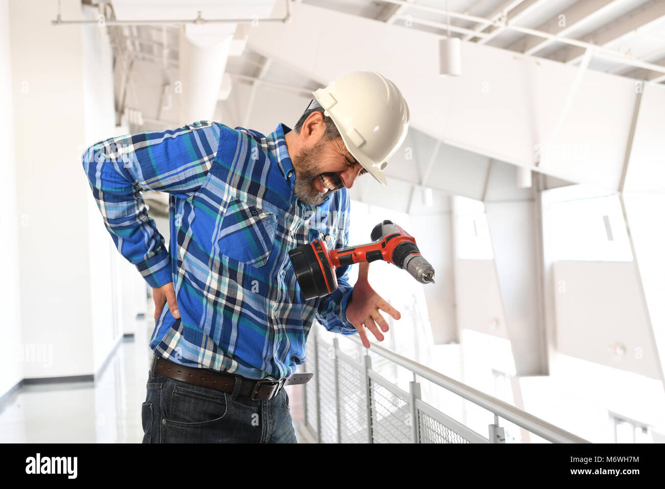 Hispanic worker getting injury to lower back inside building Stock Photo