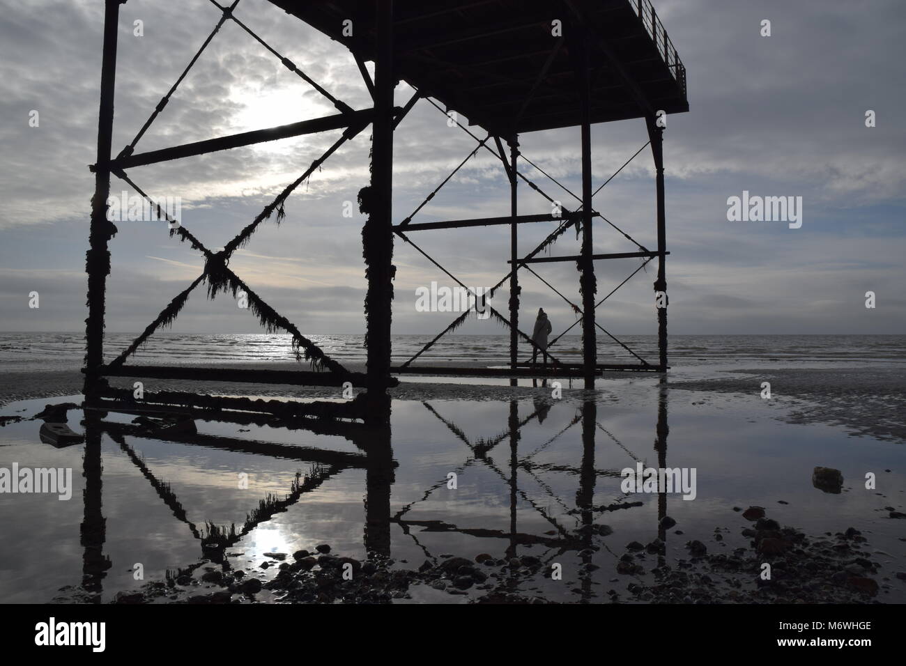 Reflections: Early morning walk along the shoreline beyond the end of the pier at low tide, Bognor Regis seafront and Victorian pier, West Sussex, UK Stock Photo