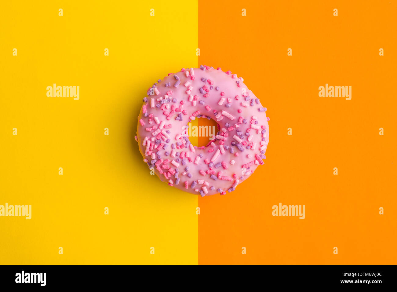 One pink donut on double colorful background. Stock Photo