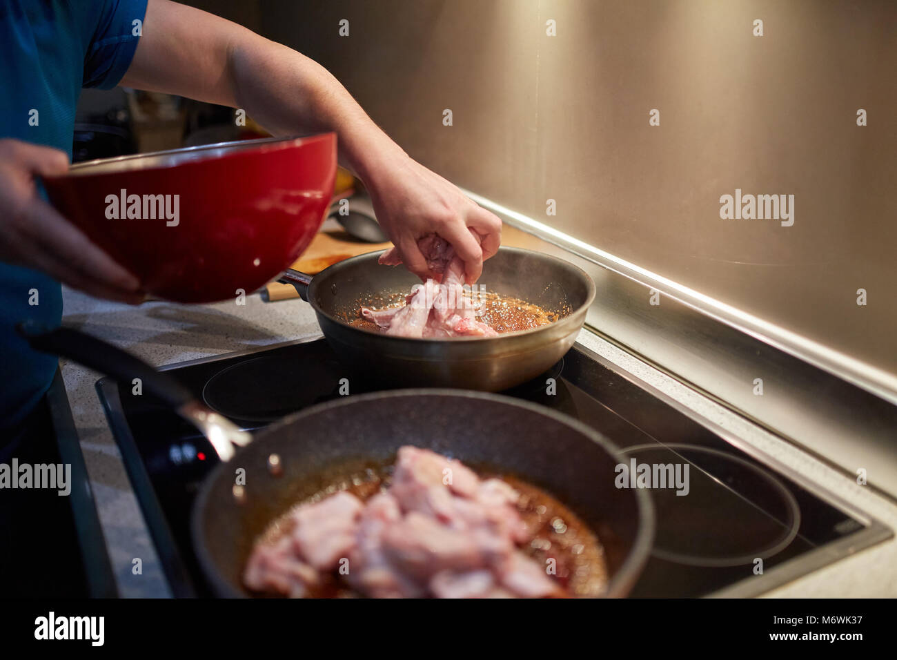 Hands of a man cooking chicken wings in wok pans Stock Photo Alamy