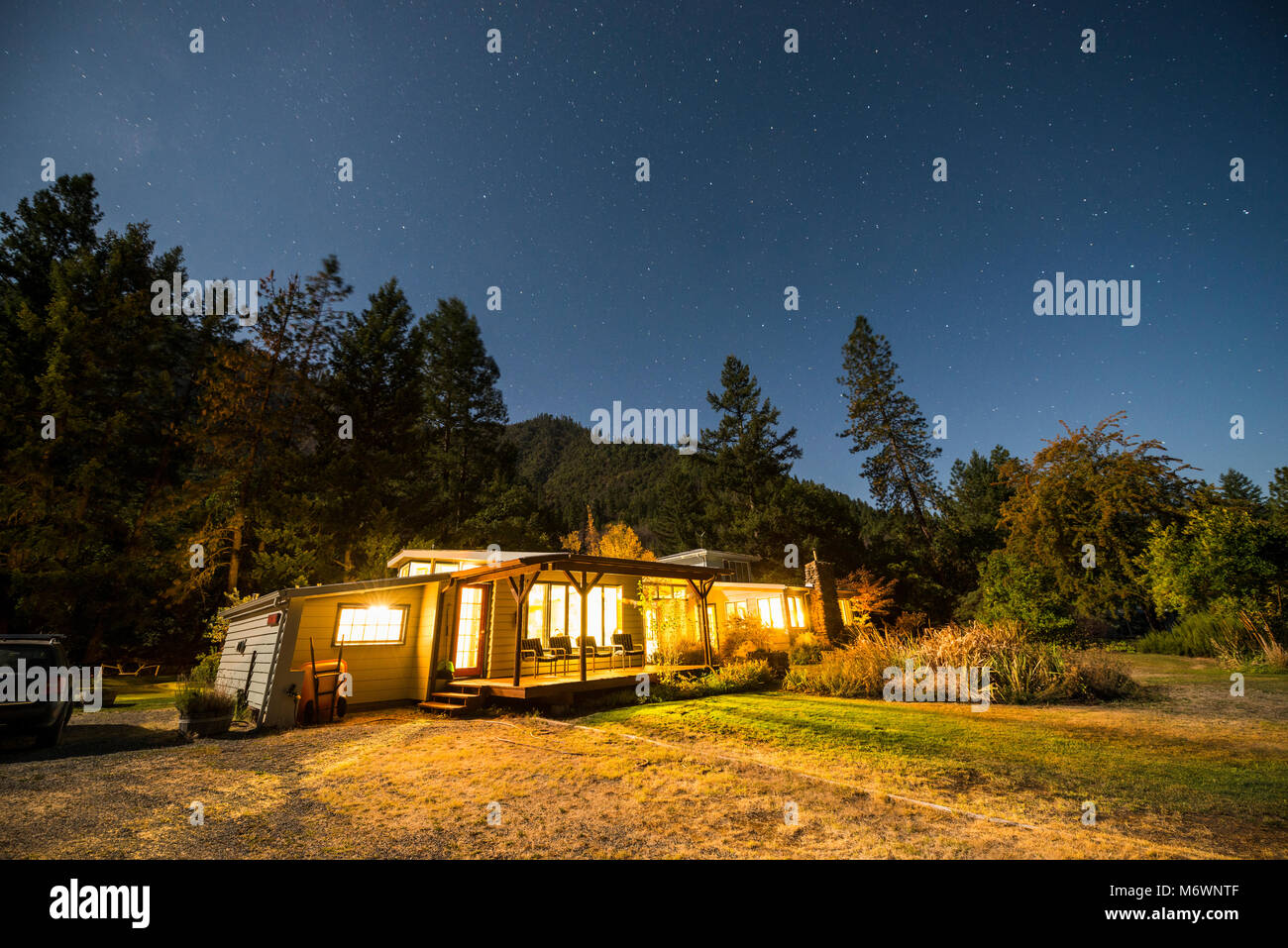 The Otter Bar Lodge and Kayak School is illuminated at night under a full moon with stars in the sky in Forks of Salmon, California. Stock Photo