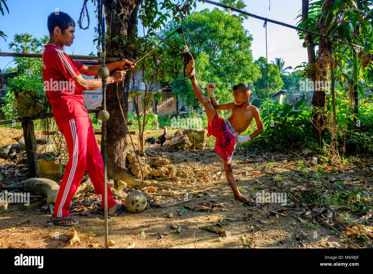 A seven years old boy is training his kickboxing skills, getting stretched by his trainer Stock Photo
