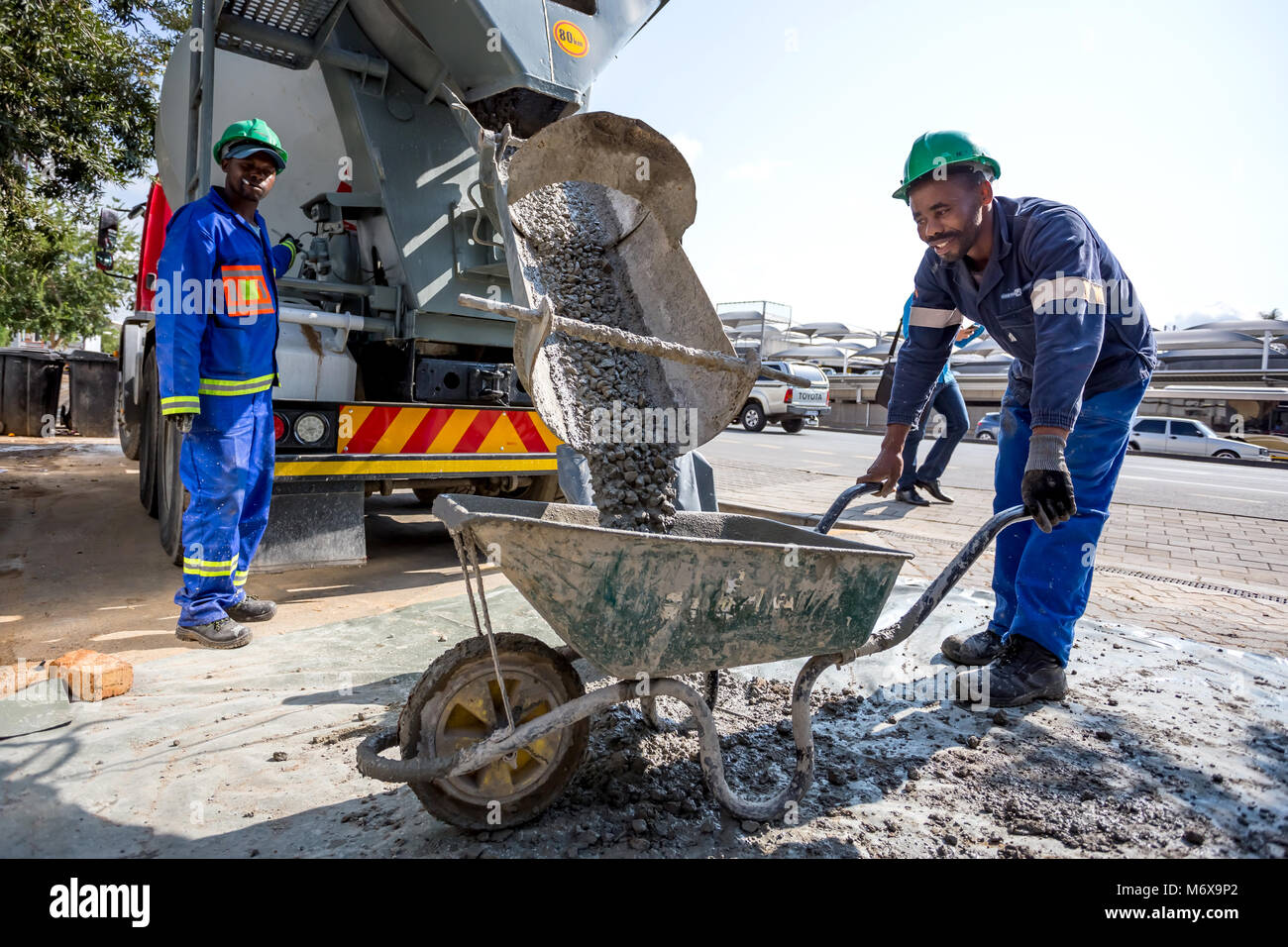Cement mixer pouring cement into wheelbarrow. Johannesburg, South