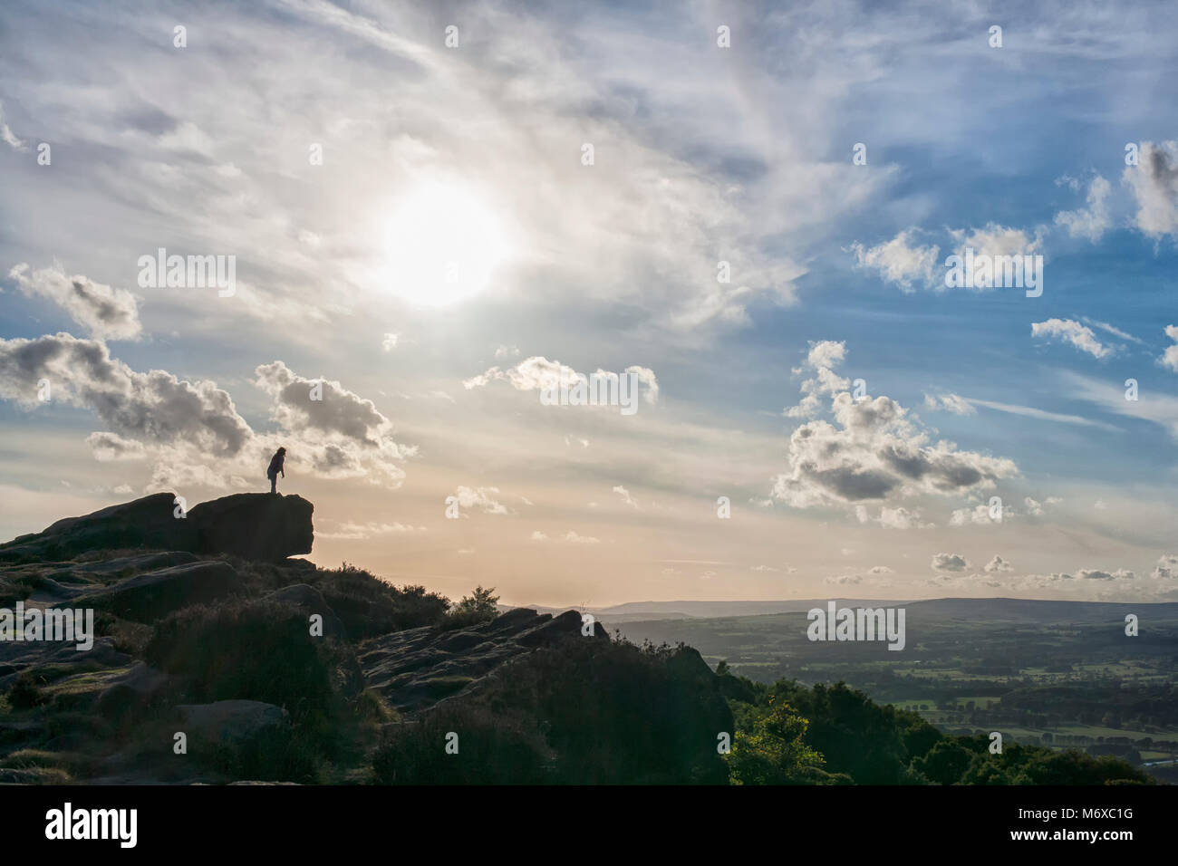 Silhouetted person on Otley Chevin watching the sun go down on a warm summers evening Stock Photo