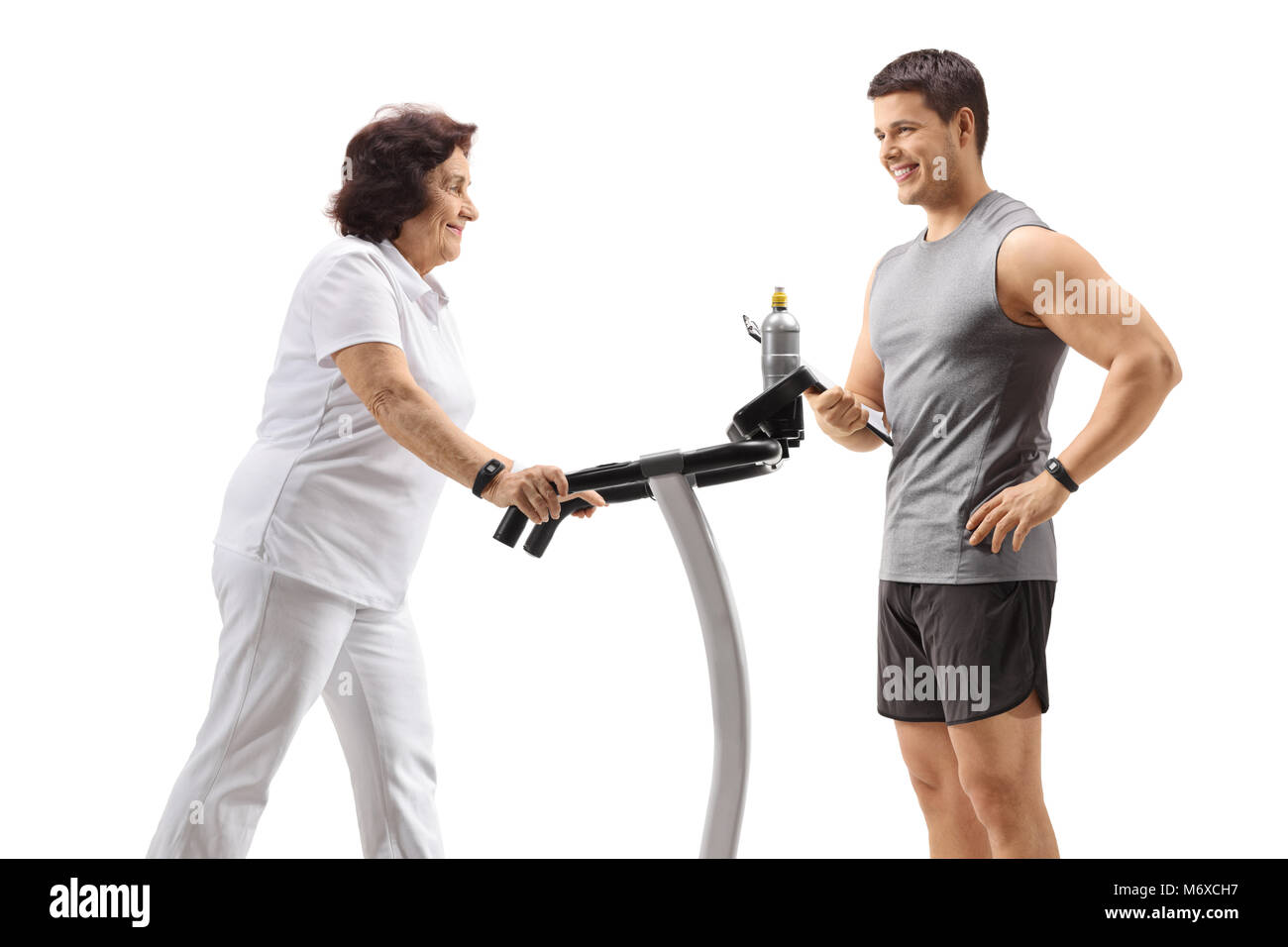Elderly woman exercising on a treadmill with a personal trainer isolated on white background Stock Photo
