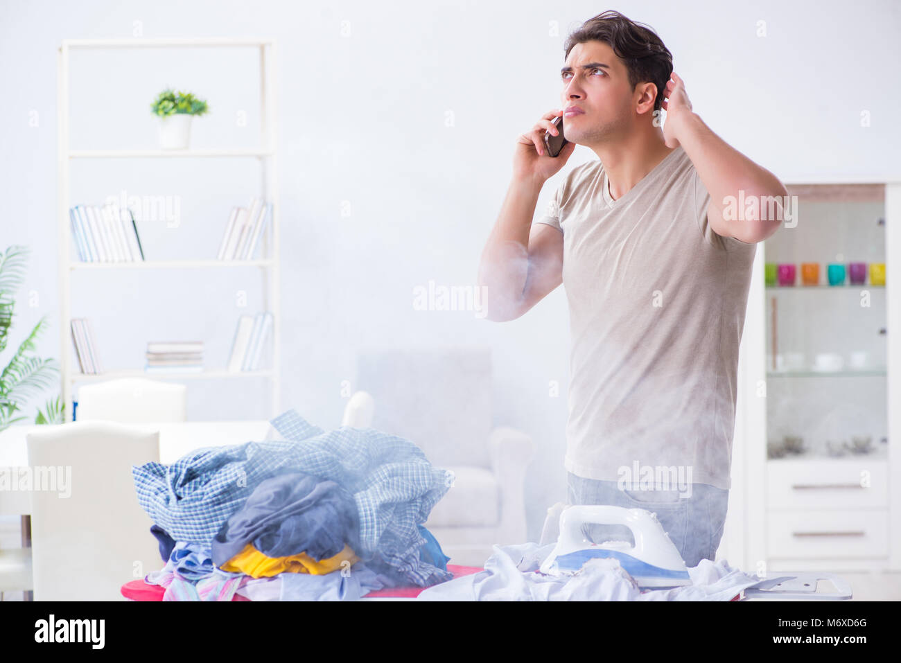 Inattentive husband burning clothing while ironing Stock Photo