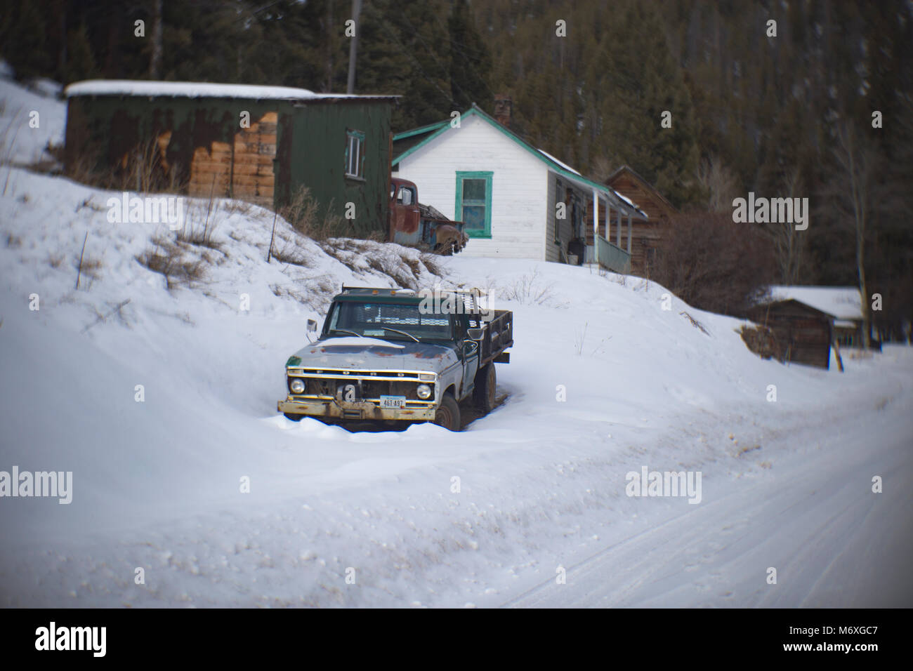 A 1978 Ford F150 stake side pickup truck, covered in the snow, in the old mining town of Tower, Granite County, Montana. Stock Photo