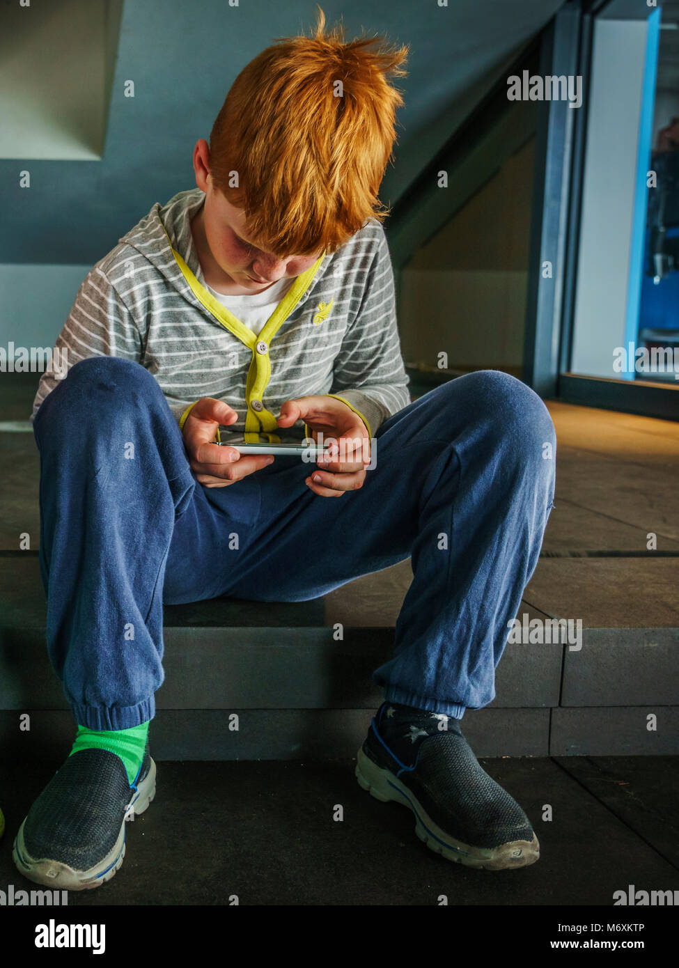 Redheaded young boy looking at a smartphone, Reykjavik, Iceland. Stock Photo