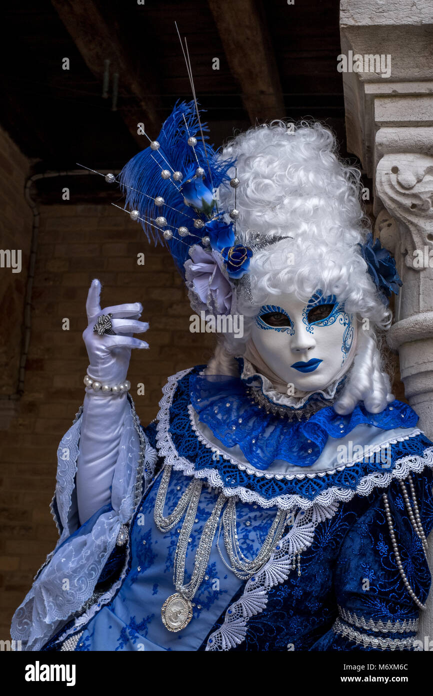 Masked woman holding ornate fan and wearing decorative blue dress ...