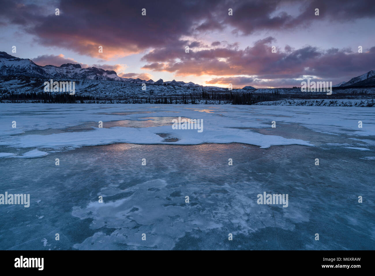 Winter sunrise over frozen Talbot Lake with snow, Jasper National Park, Canada Stock Photo