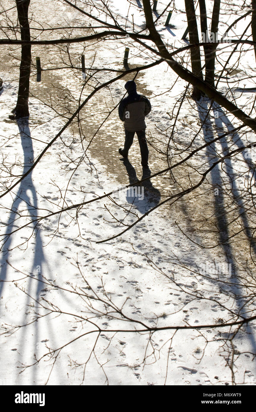 Man walking on a path through the snow in Wolomin Poland Stock Photo
