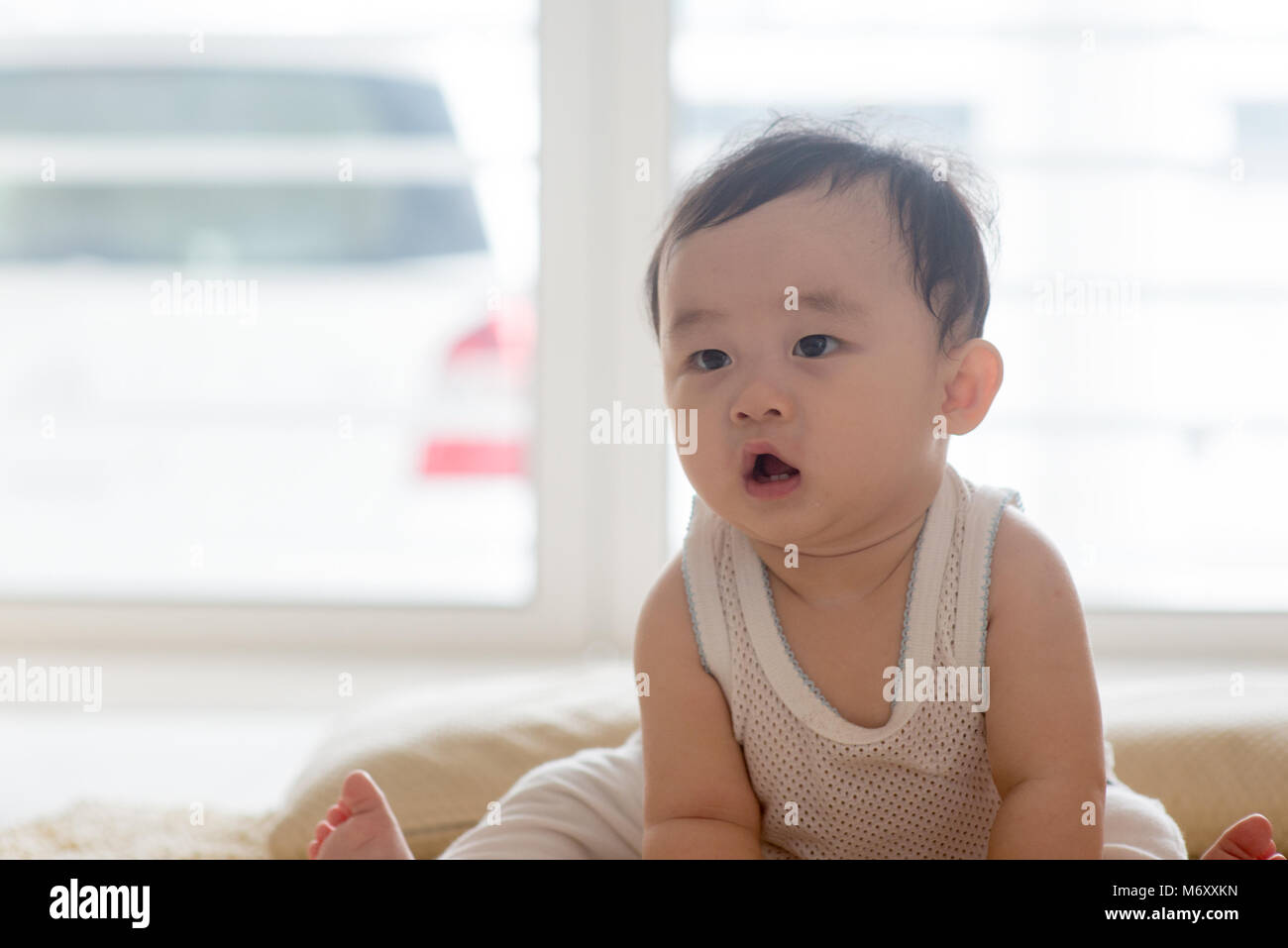 Nine months old baby boy sitting on floor. Asian family at home, living lifestyle indoors. Stock Photo