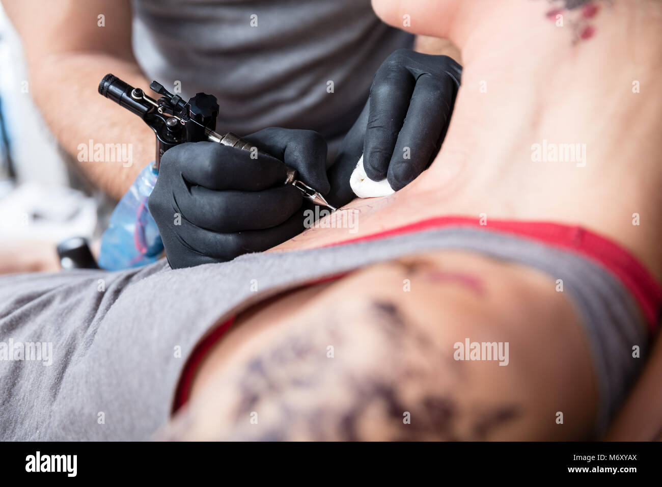 Close-up of the hands of a tattoo artist tattooing two roses Stock Photo