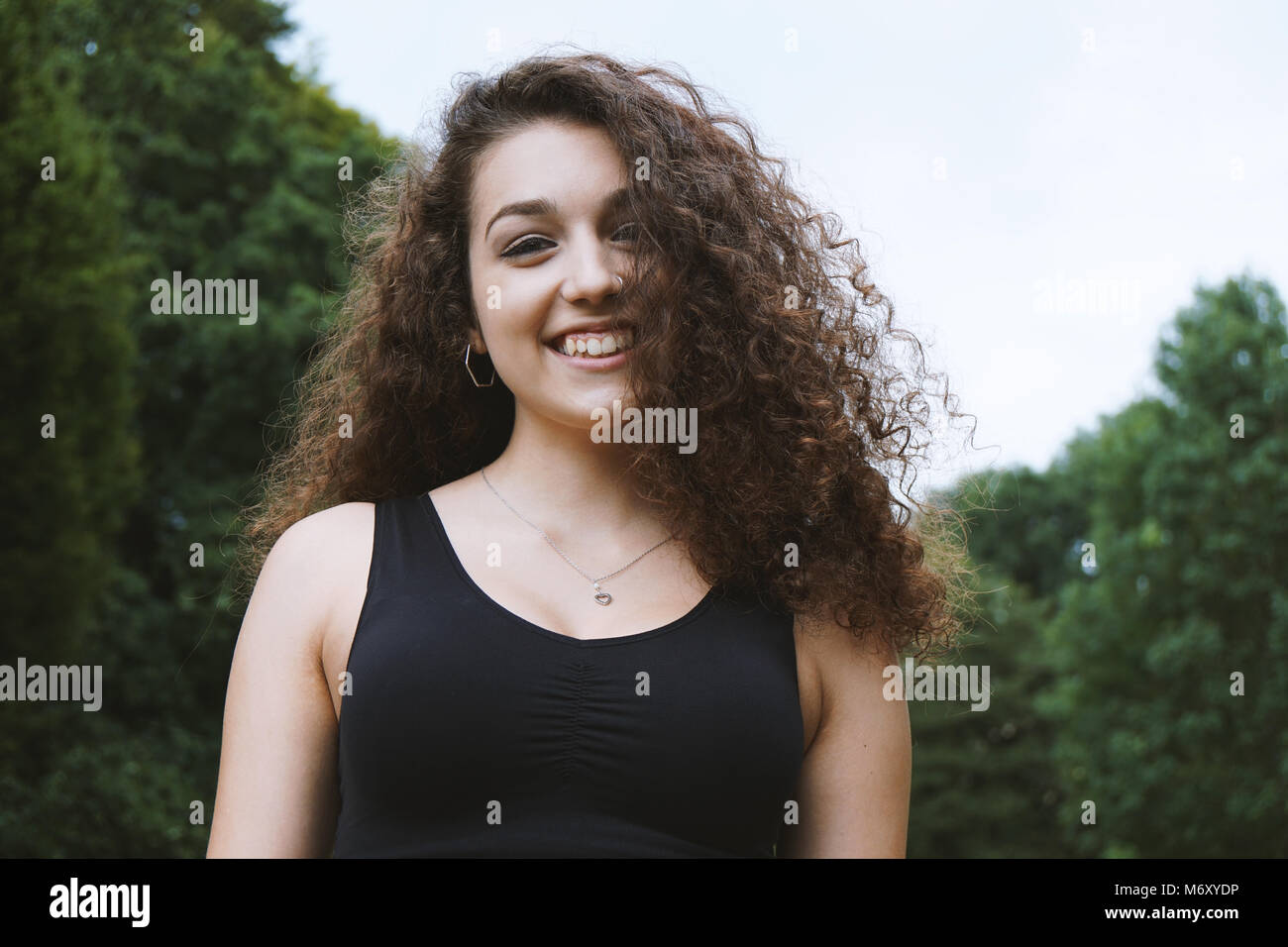 happy teenage girl with brunette long curly hair in nature Stock Photo