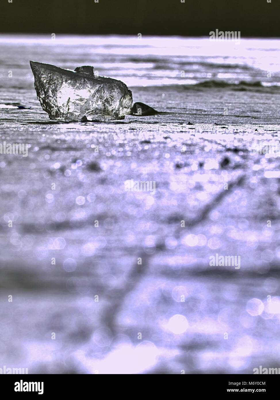 sparkling shards of cracked ice jut out on the frozen lake. The light effect occurs in deep and shallow cracks of sublime ice. Follow the depth of fie Stock Photo