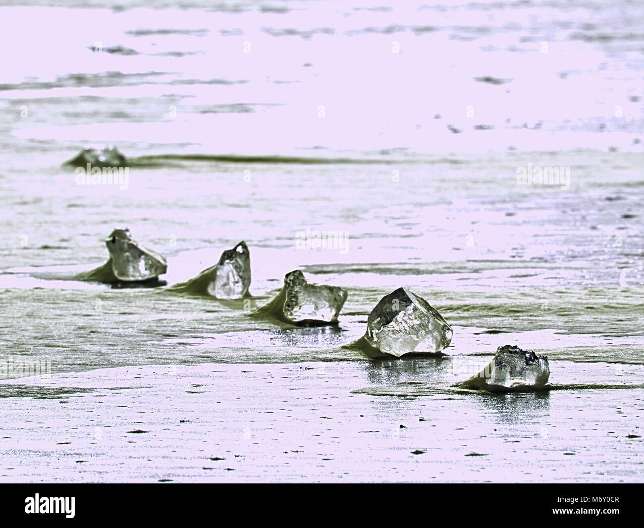 sparkling shards of cracked ice jut out on the frozen lake. The light effect occurs in deep and shallow cracks of sublime ice. Follow the depth of fie Stock Photo