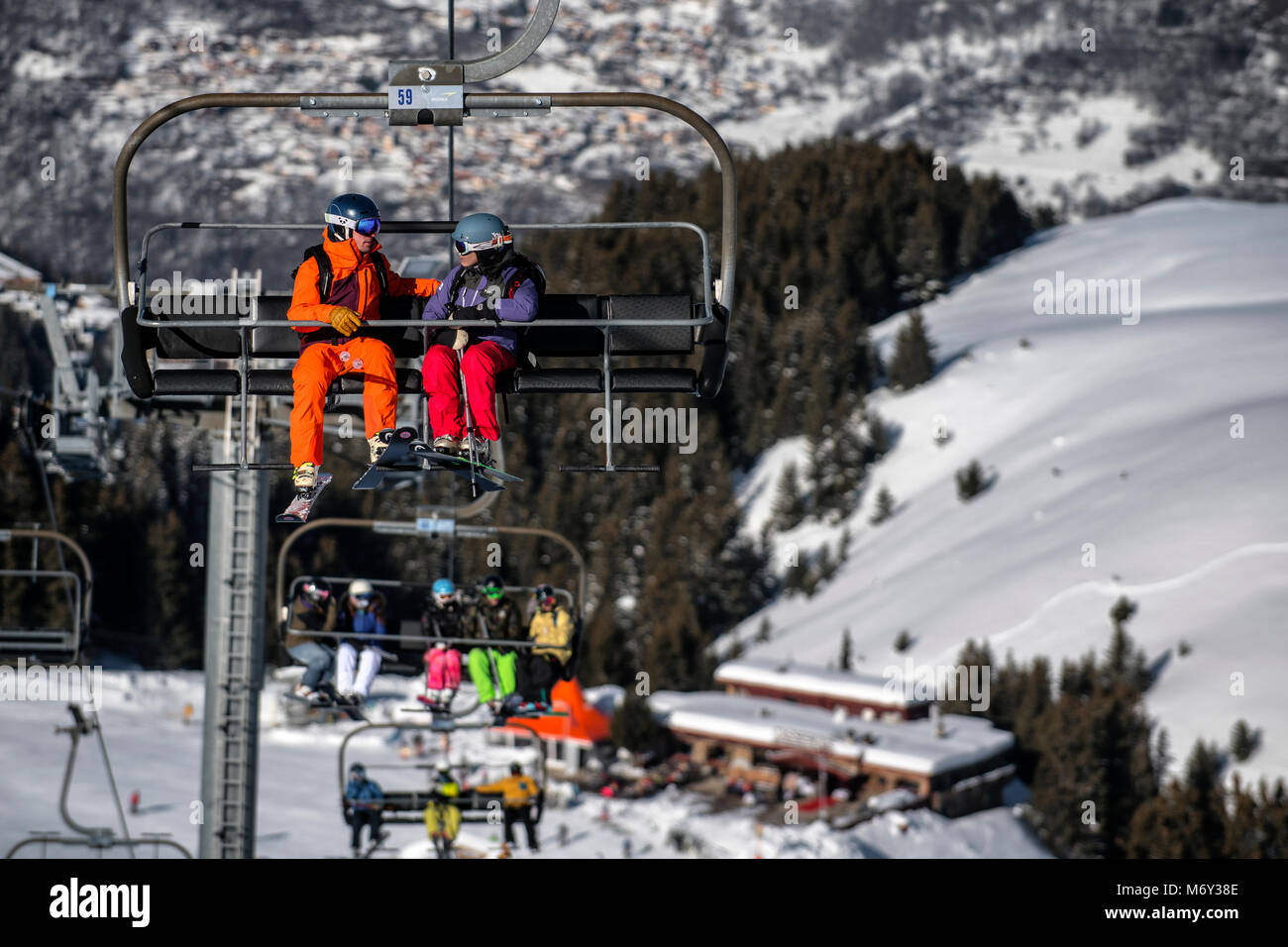 A male ski instructor speaks to a woman on a chairlift in the French Alpine resort of Courchevel. Stock Photo