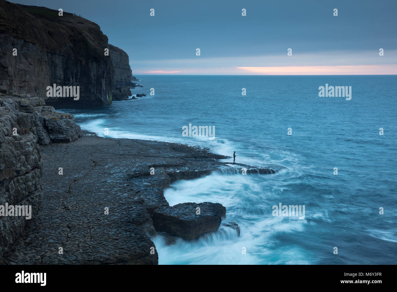 A solitary angler on Dancing Ledge at dawn, Jurassic Coast, Dorset, England, UK Stock Photo