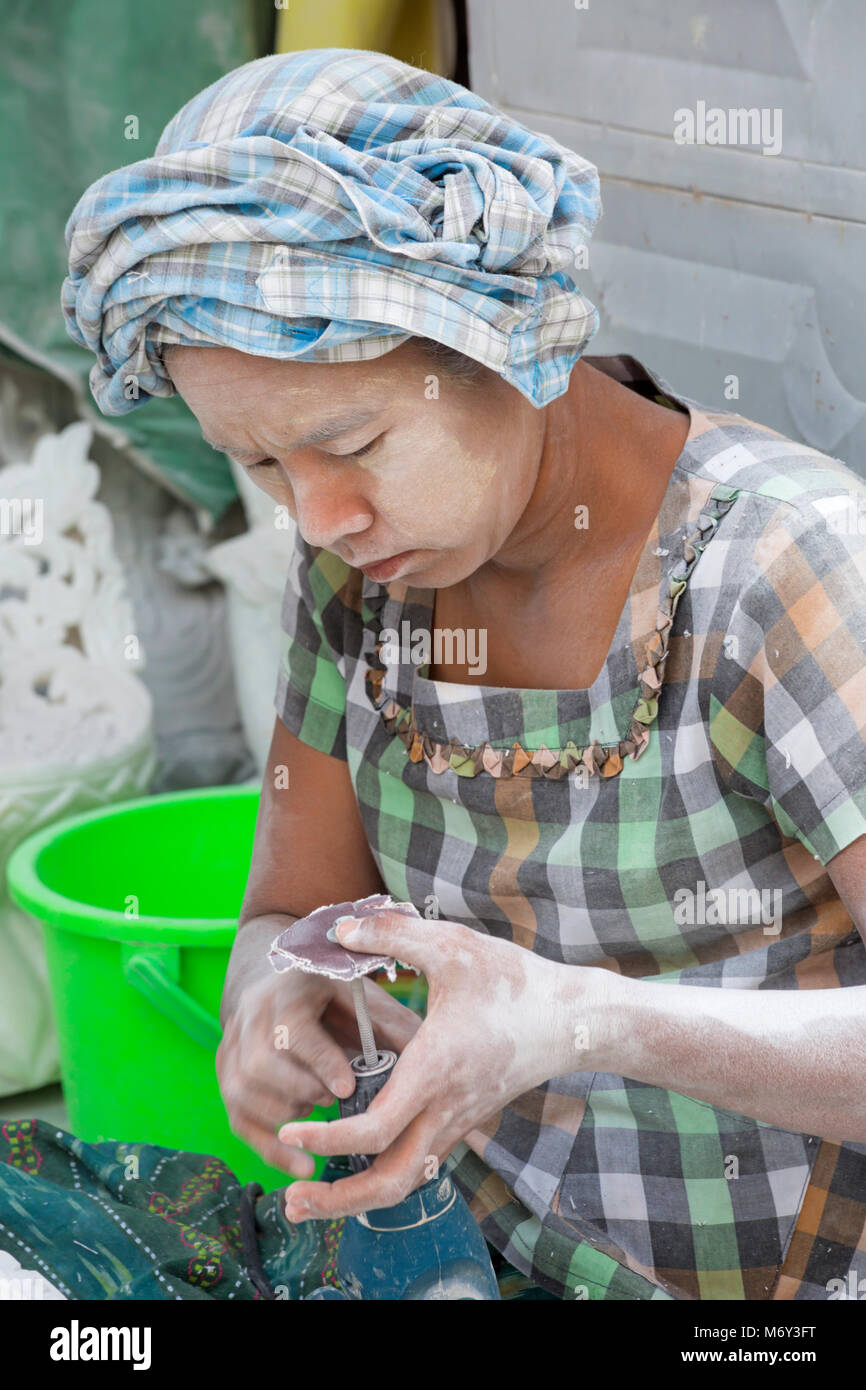 woman changing sandpaper on grinder, Amarapura Mandalay, Myanmar (Burma), Asia in February - working at marble stone carving workshops covered in dust Stock Photo