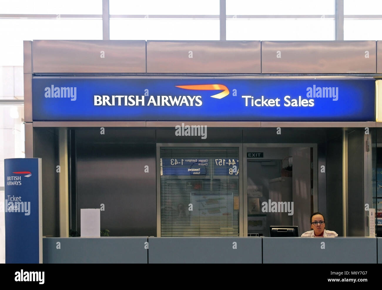 British Airways airline ticket sales counter at Athens International Airport  with agent sitting behind the desk Stock Photo